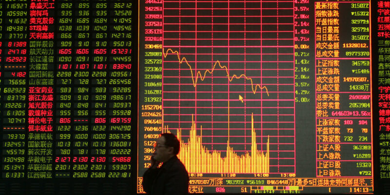 A Chinese shareholder walks by a big screen showing share prices