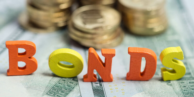 Bonds investment at wooden letters on US Dollar bills and golden coins