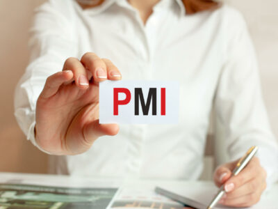 A woman in a white shirt holds a piece of paper with the text: PMI.