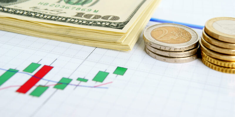 Dollar notes and euro coins on the exchange chart background