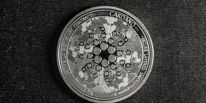 Cardano coin with logo in black and white with dark background.
