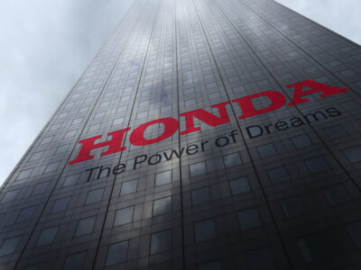Honda logo on a skyscraper facade reflecting clouds. Editorial 3D