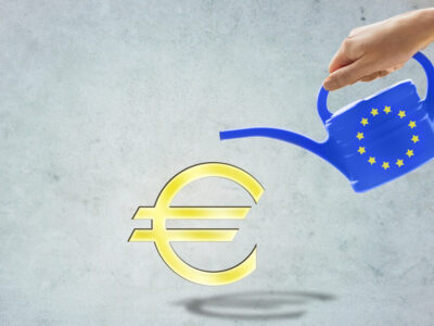 people, economics and europe concept - close up of hand holding watering can with european union stars and euro currency symbol over gray background