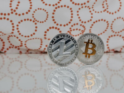 Digital currency physical silver litecoin coin and yellow bitcoin on the white table.
