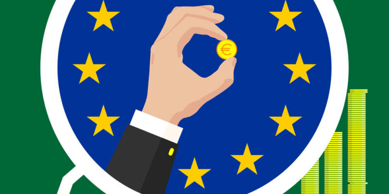 The graph of the European Union economic growth in the form of piles of gold coins, against the background of the flag and the hands of a business man in a suit with a golden euro coin. On a colored background.