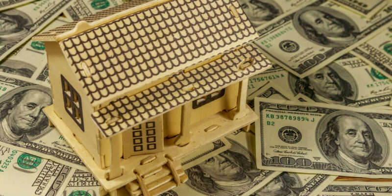 House model on background of U.S. one hundred dollar bills.