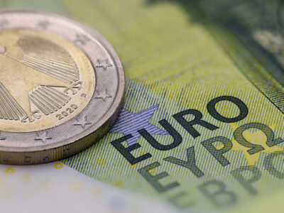 close up of euro banknote with coin, selective focus on the word EURO.