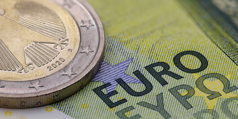 close up of euro banknote with coin, selective focus on the word EURO.