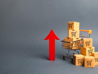 Shopping cart with cardboard boxes with a pattern of trading carts and a red up arrow. Growth wholesale and retail. Improving consumer sentiment, economic growth. Rising prices for goods, inflation