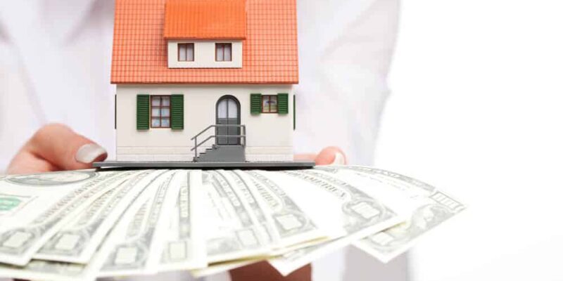 Hands with money and miniature house on a white background
