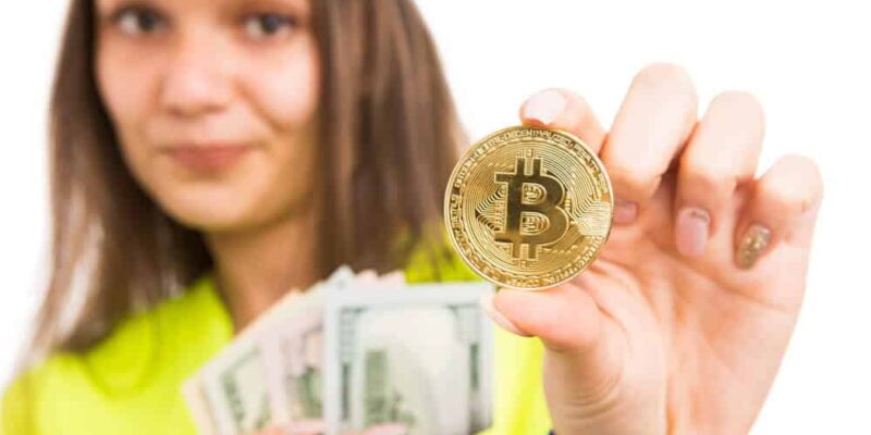 Young female architect or engineer holding cash and golden bitcoin symbol as salary payment choice concept isolated on white background