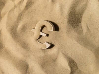 British Pound Sterling Symbol or Sign Covered with Sand in the Sun after Crisis