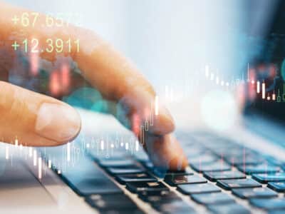 Close up of businessman hand using laptop at desktop with reative glowing forex chart on blurry background. Market analysis and trade concept
