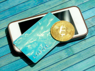Bitcoin gold coin and a gift card, credit card laying on top of a modern smartphone screen. BTC blockchain payments, mobile portable storing and payment, paying with crypto currency abstract concept