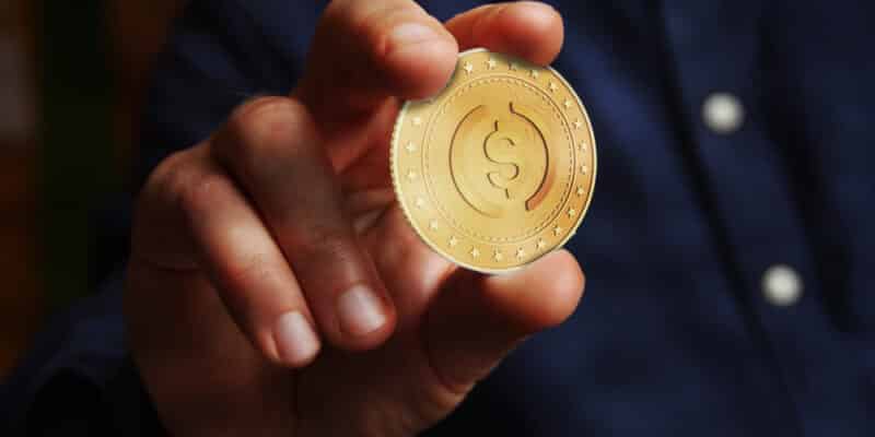 USDC cryptocurrency symbol golden USD coin in hand abstract concept.