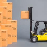 Yellow Forklift truck picks up a box on a pile of boxes. Service storage of goods in a warehouse, delivery and transportation. Freight shipping, delivery. Import and export, commodity exchange