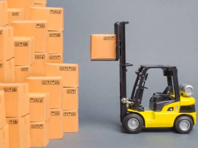 Yellow Forklift truck picks up a box on a pile of boxes. Service storage of goods in a warehouse, delivery and transportation. Freight shipping, delivery. Import and export, commodity exchange