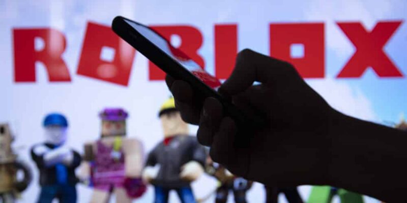 LONDON, UK - March 2021: Person holding a smartphone with Roblox game logo