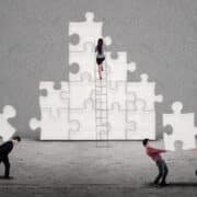 Business team building puzzles together on grey background