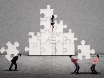 Business team building puzzles together on grey background